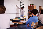 Teenage girl writing on whiteboard in classroom