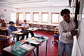 Teenagerin schreibt im Klassenzimmer an die Tafel