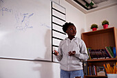 Teenager-Mädchen steht vor einer Tafel im Klassenzimmer