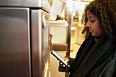 Frau vor einem Fahrkartenautomaten stehend