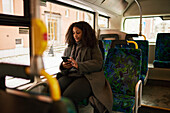 Frau im Bus benutzt Mobiltelefon