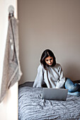 Young woman using laptop on bed