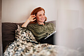 Lächelnde Frau mit Laptop auf dem Bett