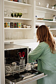 Woman standing near open dishwasher