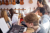 Teenagers and teacher during keyboard lesson