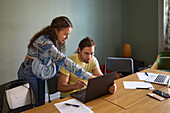 Coworkers in boardroom using laptop