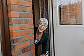 Ältere Frau schaut durch die offene Tür
