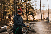 Woman using water hose in forest