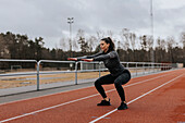 Woman doing squats at running track