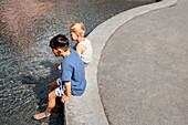 Child friends sitting with feet in pond