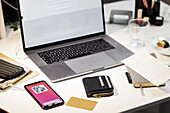 View of desk with laptop, cell phone and credit card
