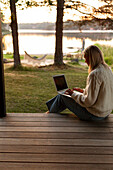 Frau mit Laptop auf der Veranda