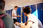 Teenager-Jungen benutzen ein Handy in der Umkleidekabine