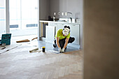 Arbeiter beim Verlegen eines Fußbodens in der Küche