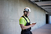 Arbeiter benutzt Handy auf der Baustelle