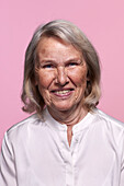 Porträt einer lächelnden älteren Frau vor rosa Hintergrund