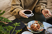 Woman drinking tea and eating cinnamon bun