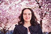 Porträt einer jungen Frau, die unter einer Kirschblüte steht