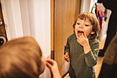 Junge steht mit offenem Mund vor einem Spiegel