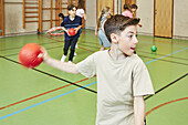 Junge wirft Ball während des Sportunterrichts in der Schulsporthalle