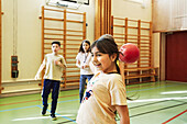 Mädchen wirft Ball im Sportunterricht in der Schulsporthalle