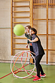 Kinder spielen mit Hula-Hoop-Reifen in der Schulturnhalle