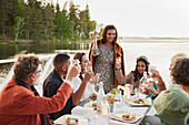 Family raising toast during dinner by lake