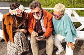 People sitting on bench and using phone