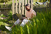 Mann mit Laptop im Garten