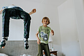 Brothers jumping on bed at home