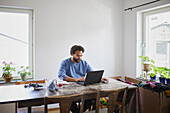Mann arbeitet von zu Hause aus am Laptop