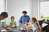 Vater mit Kindern sitzt am Tisch und isst eine Kleinigkeit