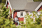 Woman using laptop in front of house