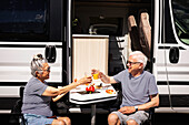 Älteres Paar sitzt vor einem Wohnwagen