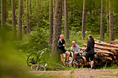 Cyclists resting on logs in forest