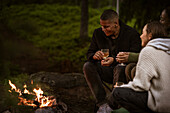 Freunde sitzen am Lagerfeuer und trinken Wein