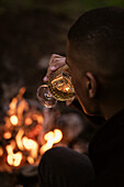 Man drinking wine by campfire