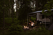 Freunde zelten im Wald und sitzen am Lagerfeuer
