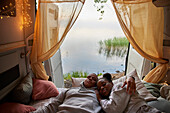 Young couple lying in bed in camper van