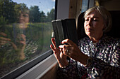 Senior woman taking picture through train window