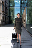 Businesswoman walking with wheeled luggage