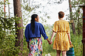 Weibliches Paar hält sich im Wald an den Händen