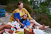 Weibliches Paar beim Picknick und beim Lesen eines Buches