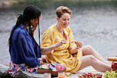 Female couple having picnic by river