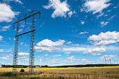 Electricity pylons and wind turbine against blue sky