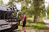 Cyclist standing near van with bicycles on rack