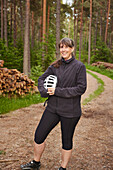 Portrait of woman holding bike helmet in forest