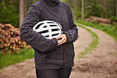 Woman holding bike helmet in forest