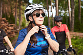 Female cyclist putting on bike helmet