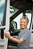 Porträt einer lächelnden älteren Frau, die in einen Van steigt